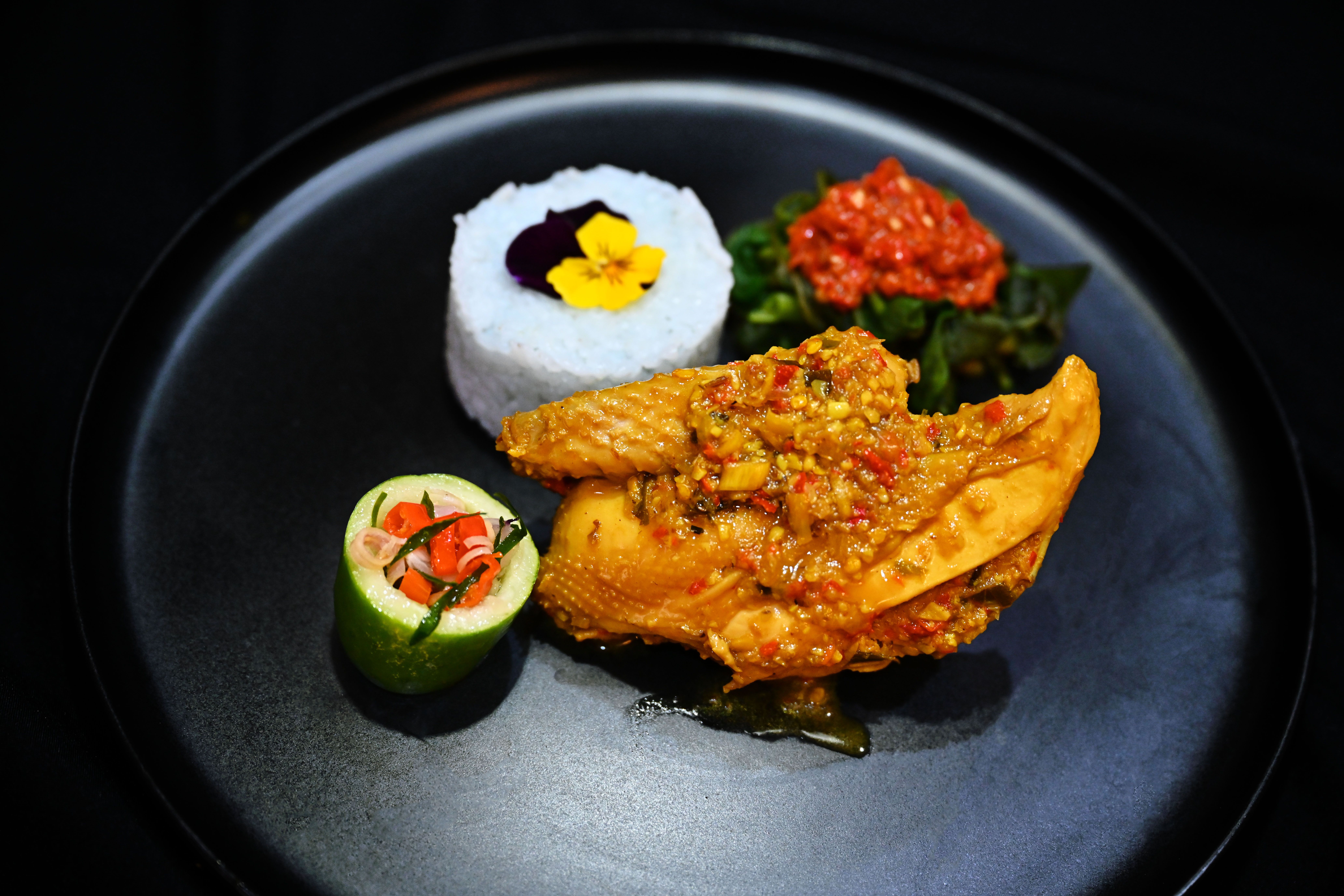 A beautifully plated dish of Ayam Betutu served with rice and vegetables in Bandung, Indonesia.