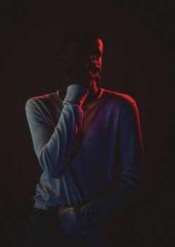 Dramatic portrait of a person in silhouette with contrasting red and blue lighting.