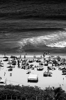 Crowded beach in Rio de Janeiro captured in high-contrast black and white with people and umbrellas.