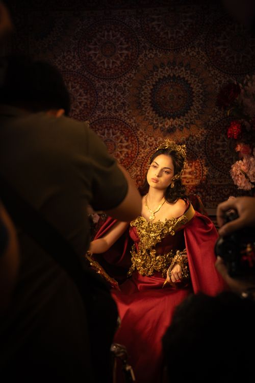 Free A model in an elaborate red gown poses for a professional portrait session indoors. Stock Photo