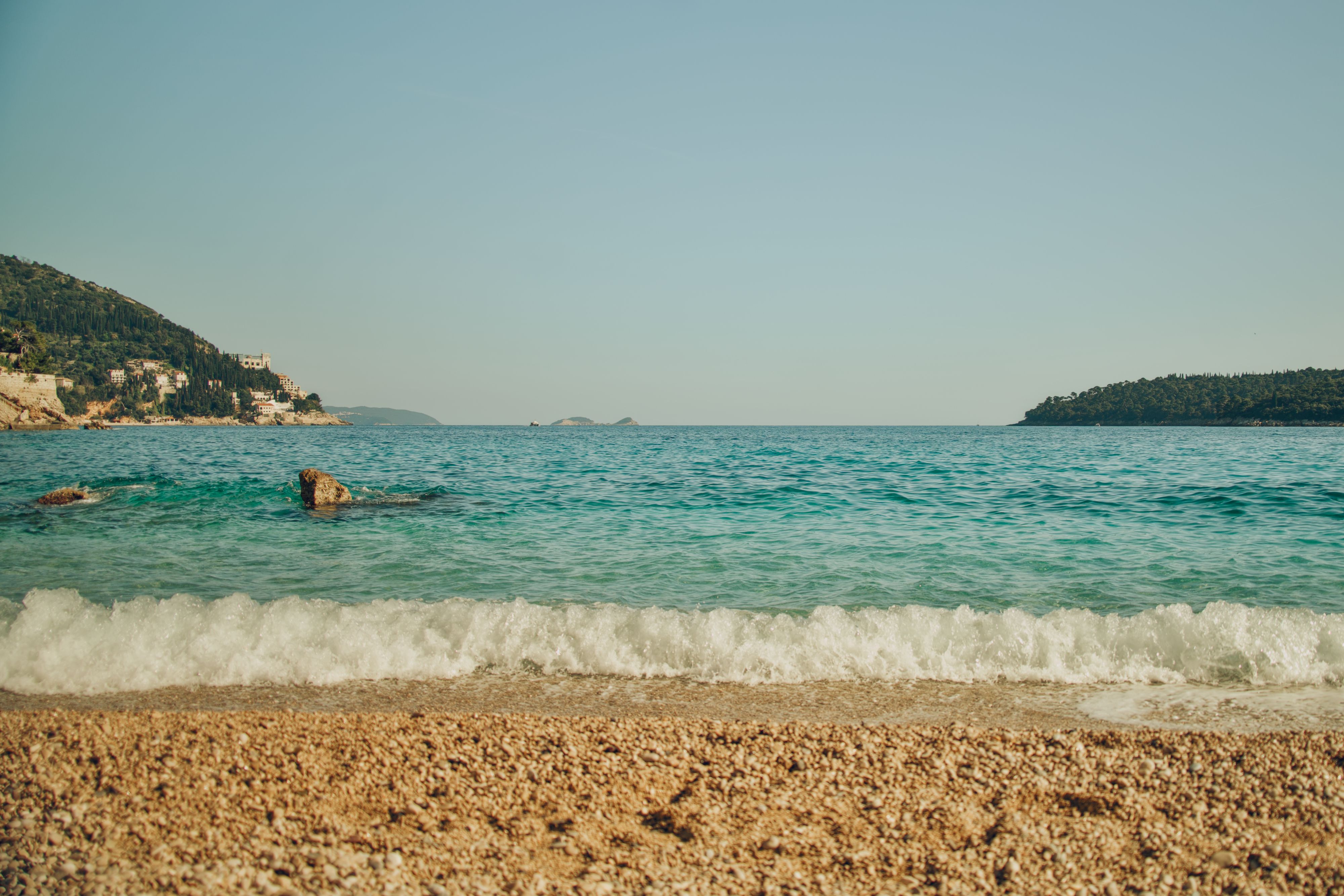 Pebble beach with clear turquoise water and pine trees near Dubrovnik