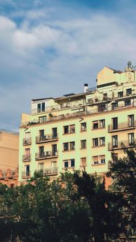 Charming apartment building in Barcelona on a sunny day with lush greenery.