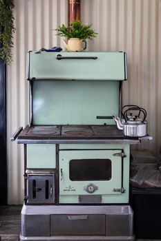 A classic mint-green vintage stove with a teapot and plant décor in a cozy kitchen setting.