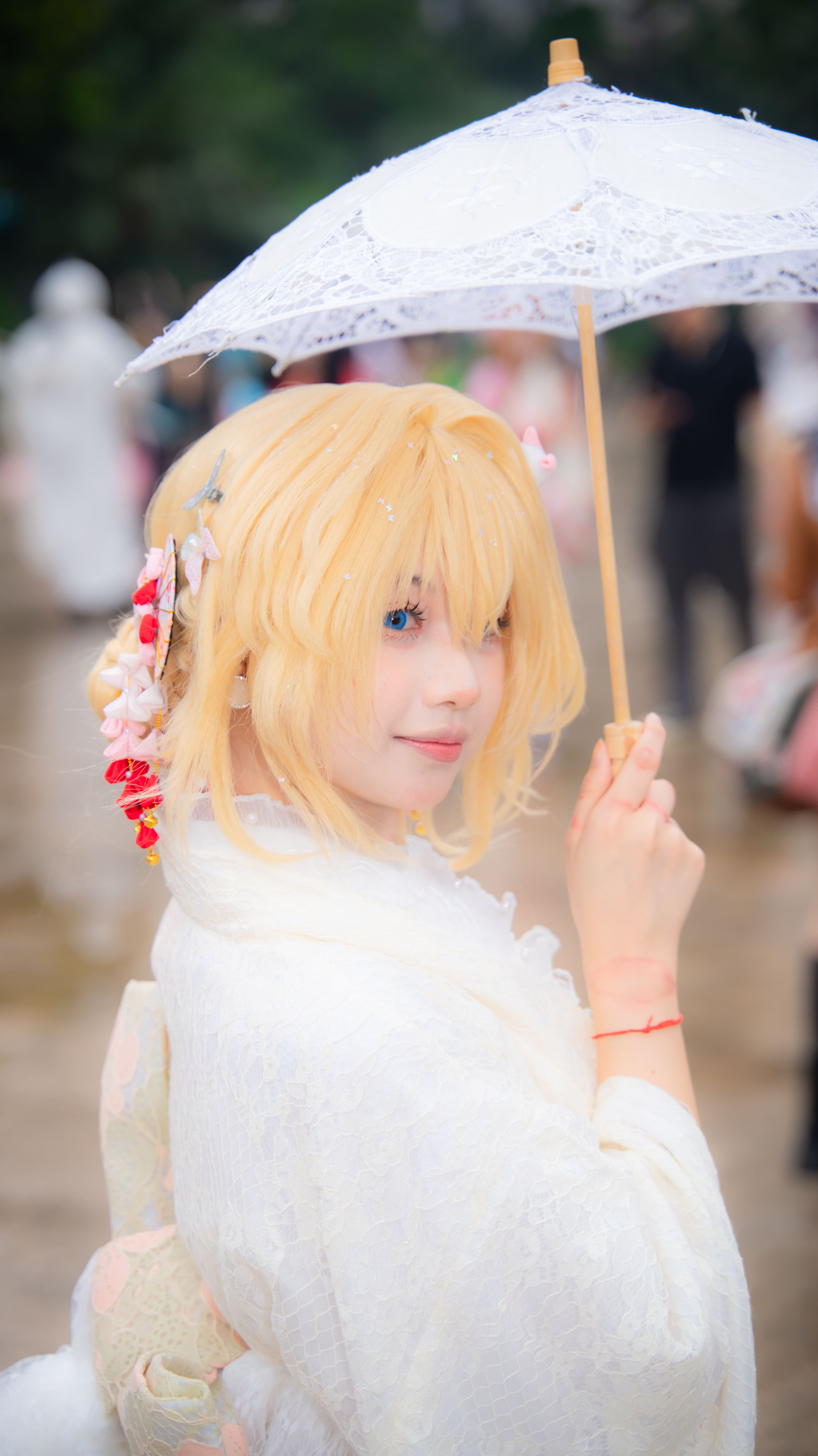 Anime-inspired cosplayer with umbrella outdoors, dressed in traditional attire.