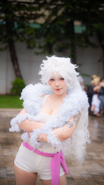 Cosplayer in fantasy costume with white hair poses confidently outdoors.