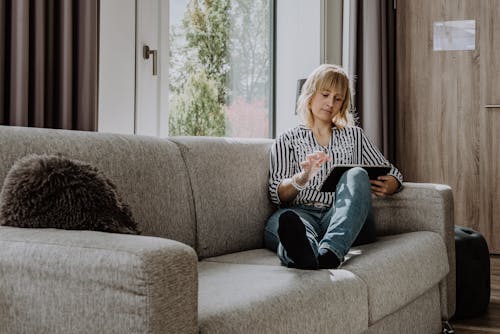 Free Mature woman using tablet on cozy sofa Stock Photo