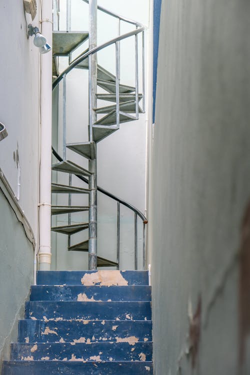 免費 黑色金屬螺旋樓梯，靠近藍色塑料箱 圖庫相片