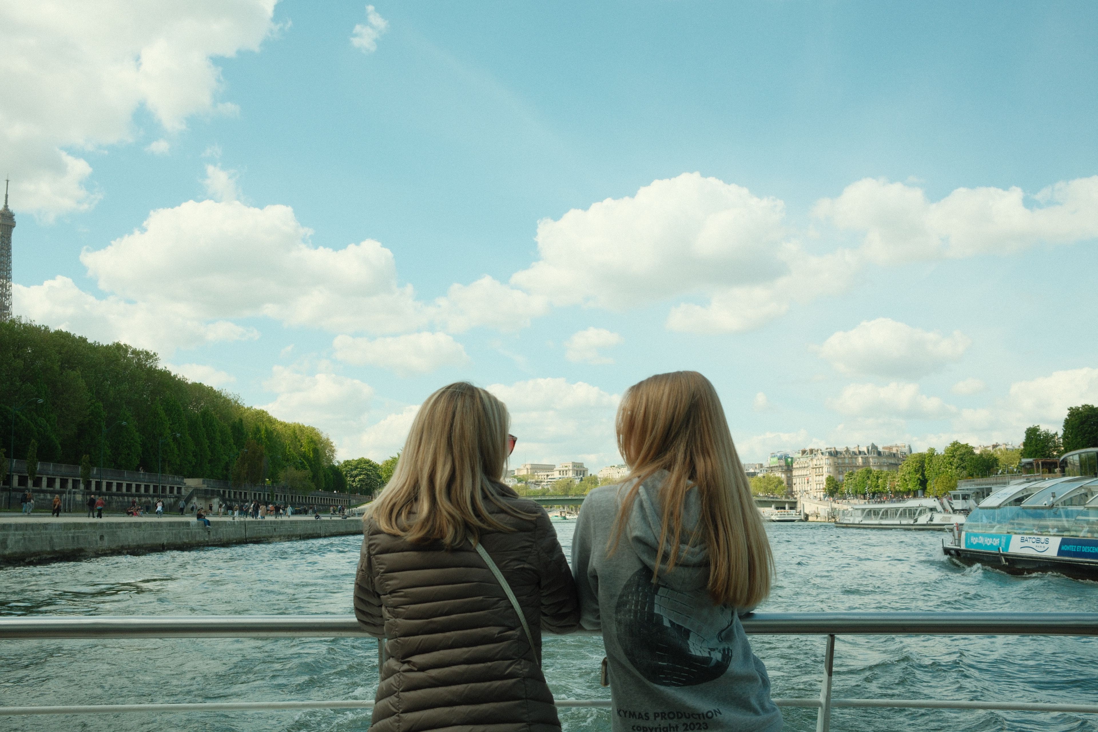 Two women enjoy a peaceful cruise on the Seine River in Paris, with a view of the Eiffel Tower. Two women enjoy a peaceful cruise on the Seine River in Paris, with a view of the Eiffel Tower.