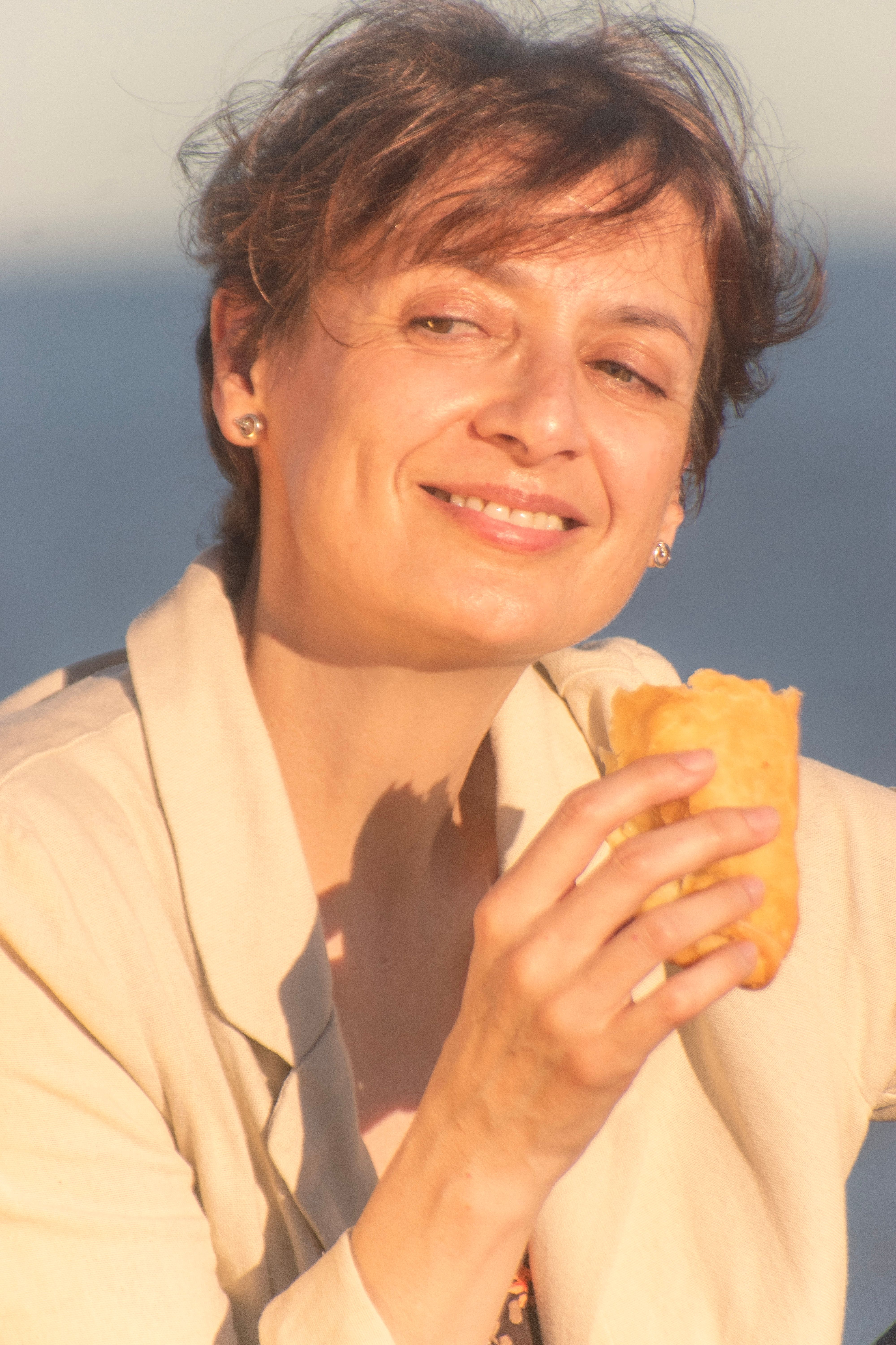 A woman savoring a snack by the seaside during a sunny day in Montevideo, Uruguay.