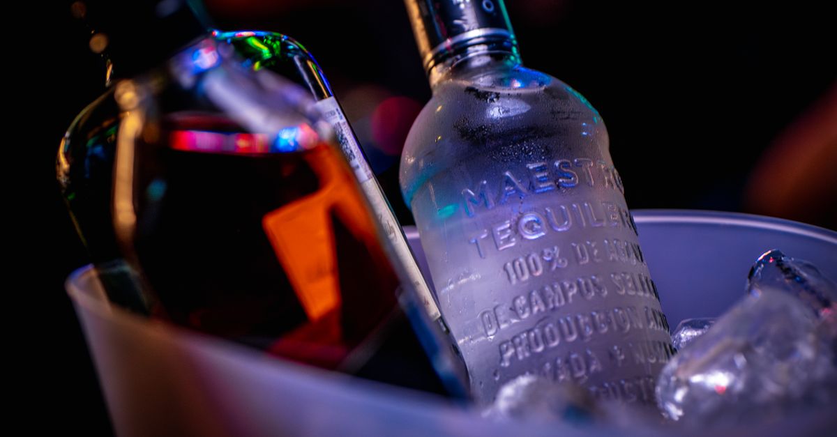 Vibrant close-up of tequila bottles in an ice bucket at night, capturing nightlife ambience.