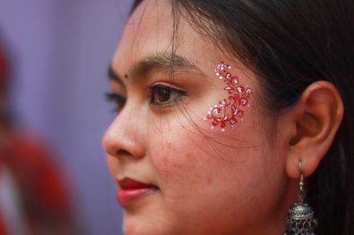 Free Close-up of woman's side profile with intricate face paint and traditional earrings, blending modern and cultural style. Stock Photo