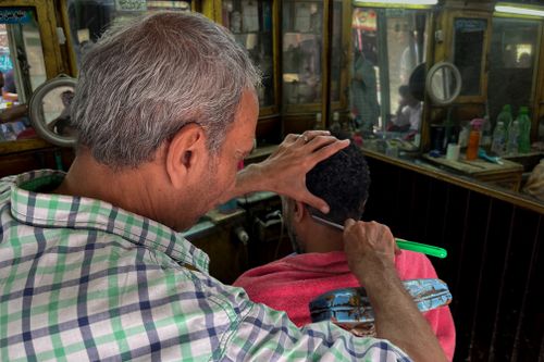 Free Inside a Cairo barber shop, a man receives a haircut with traditional tools. Stock Photo