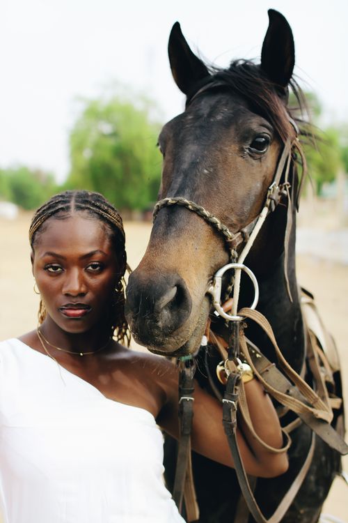 Free A striking woman posing confidently next to a majestic horse, depicting elegance and strength. Stock Photo