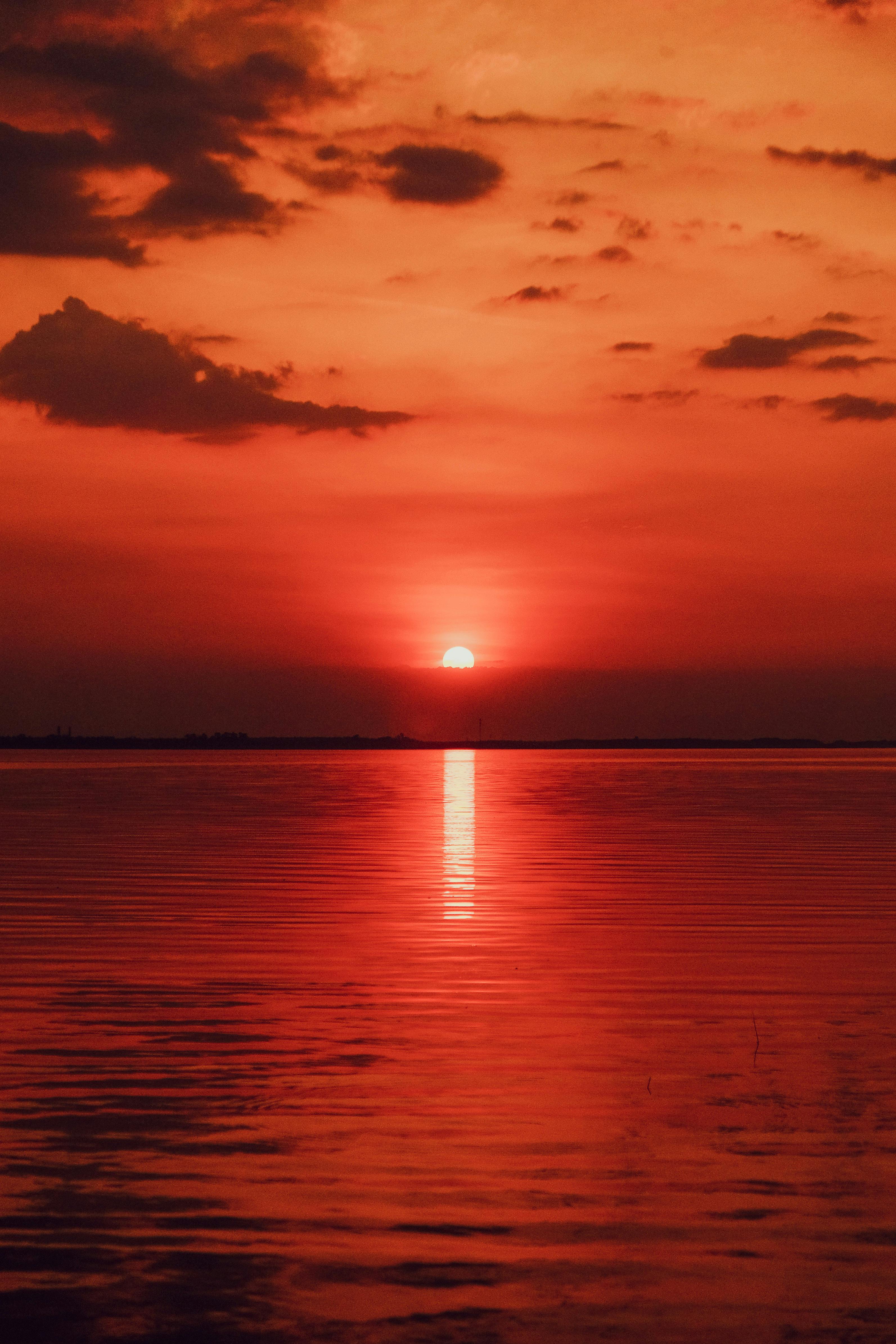 Captivating red sunset over a tranquil body of water, reflecting vibrant hues.