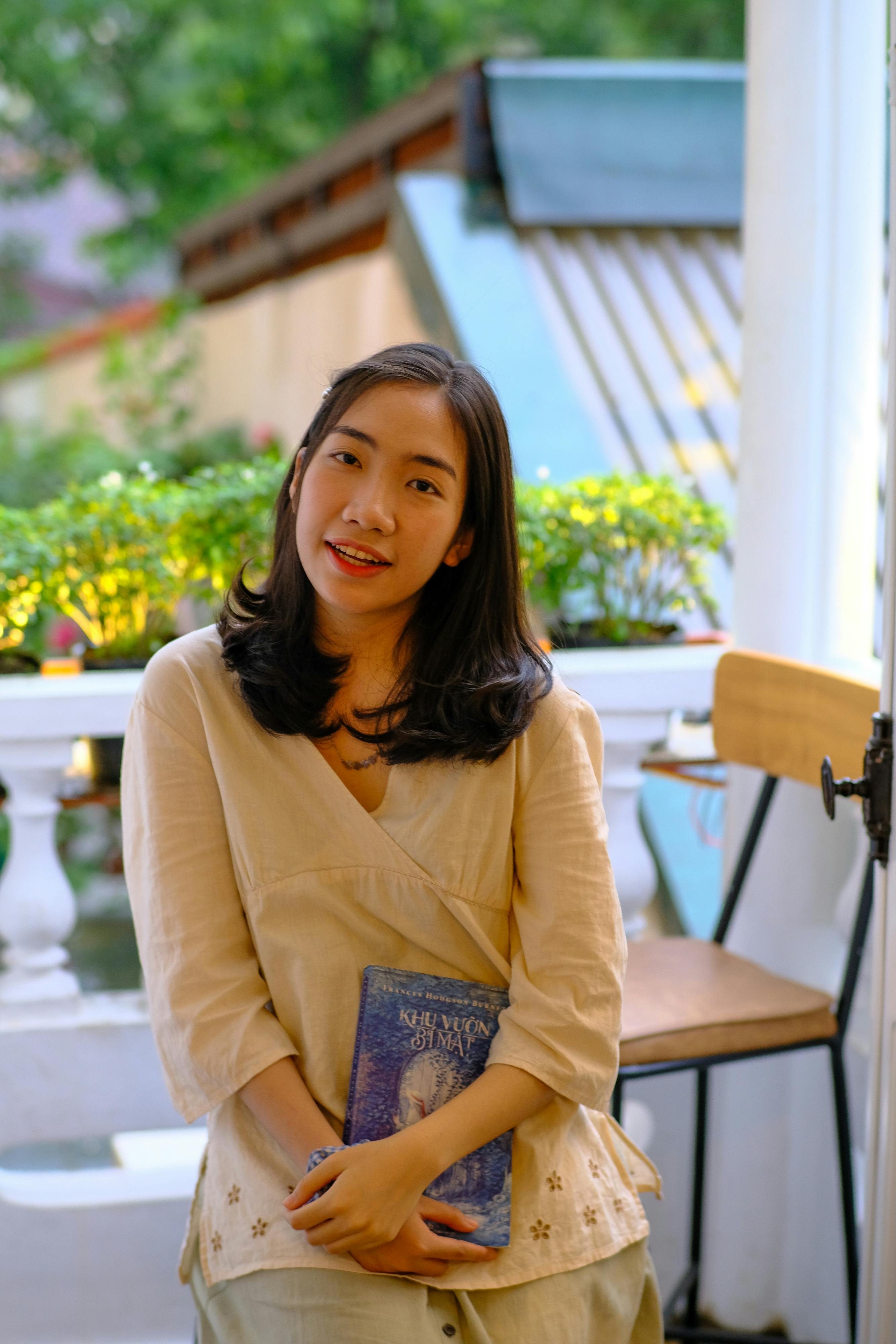 A serene portrait of a woman with a book, sitting outdoors in Hue, Vietnam.