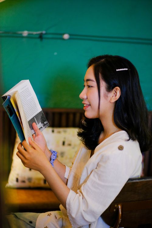 Free Young woman enjoying a book at a vibrant cafe in Hue, Vietnam. Stock Photo