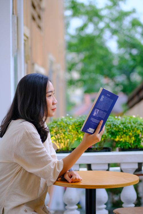 Free Side profile of a woman reading a book outdoors on a sunny day. Stock Photo