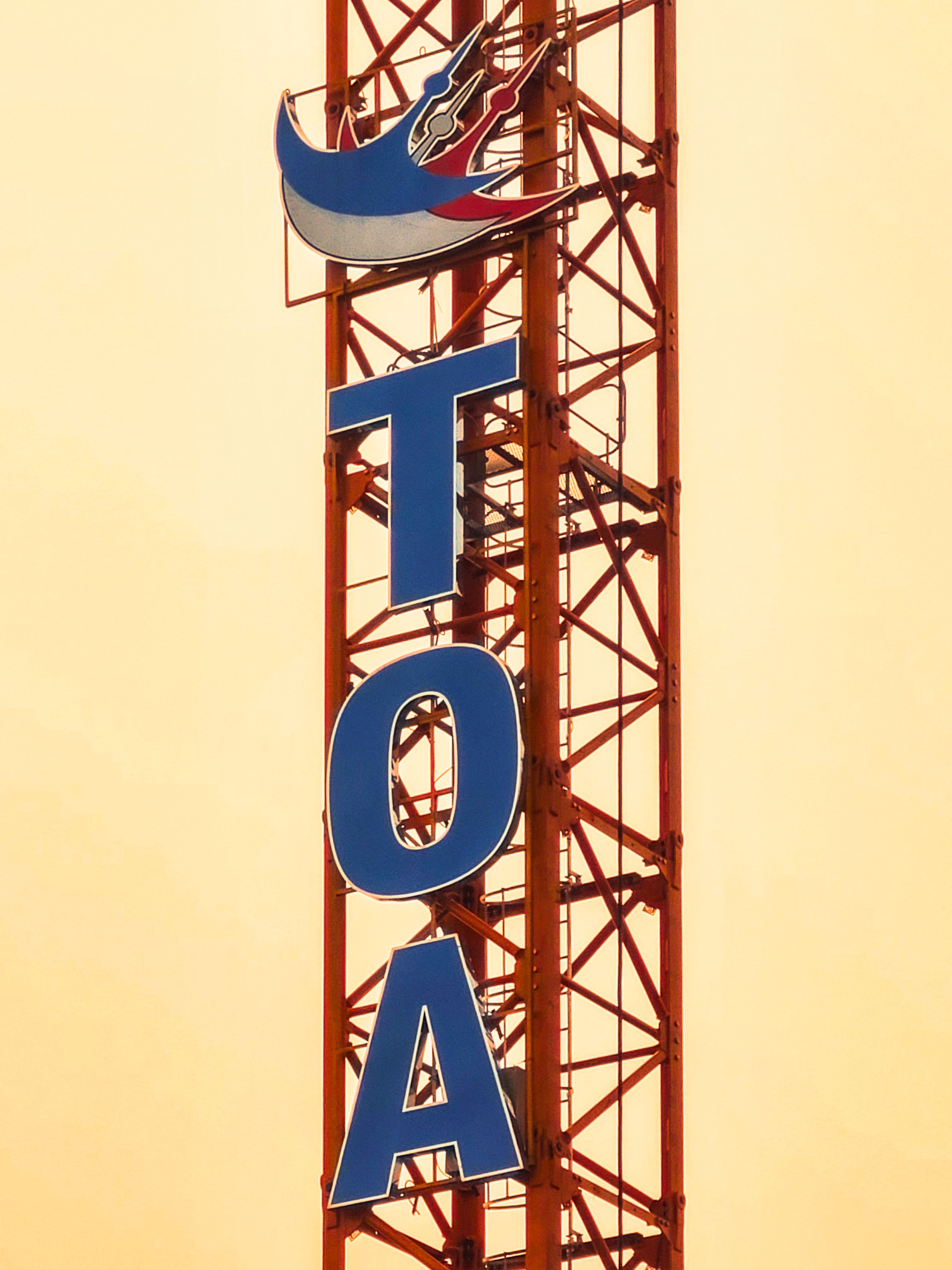 Vertical TOA sign on a tower with an orange sky backdrop, representing urban construction.