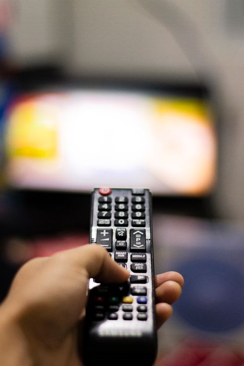 Person holding a remote control while watching television