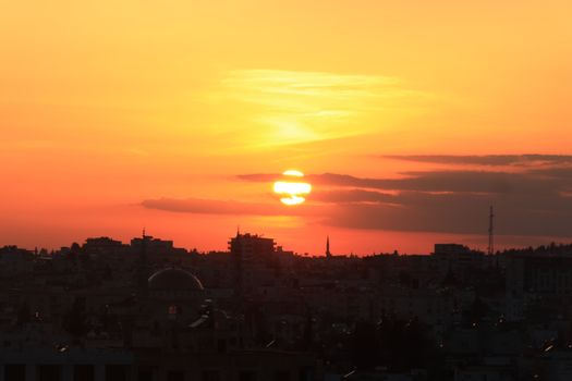 Beautiful sunset casting vibrant colors over a cityscape, silhouetting the skyline.