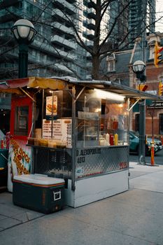 A bustling hot dog stand on an urban street corner, offering fast food in a cityscape.
