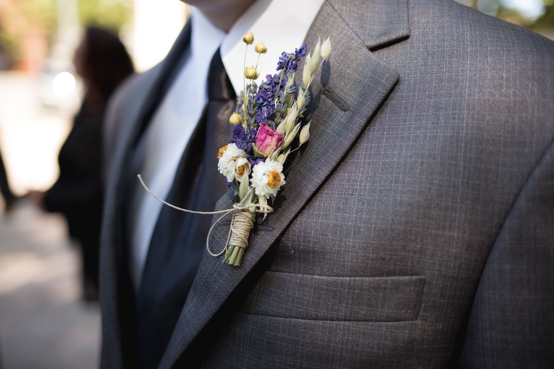 Close-up of an elegant groom wearing a designer suit and floral boutonniere during a wedding ceremony.