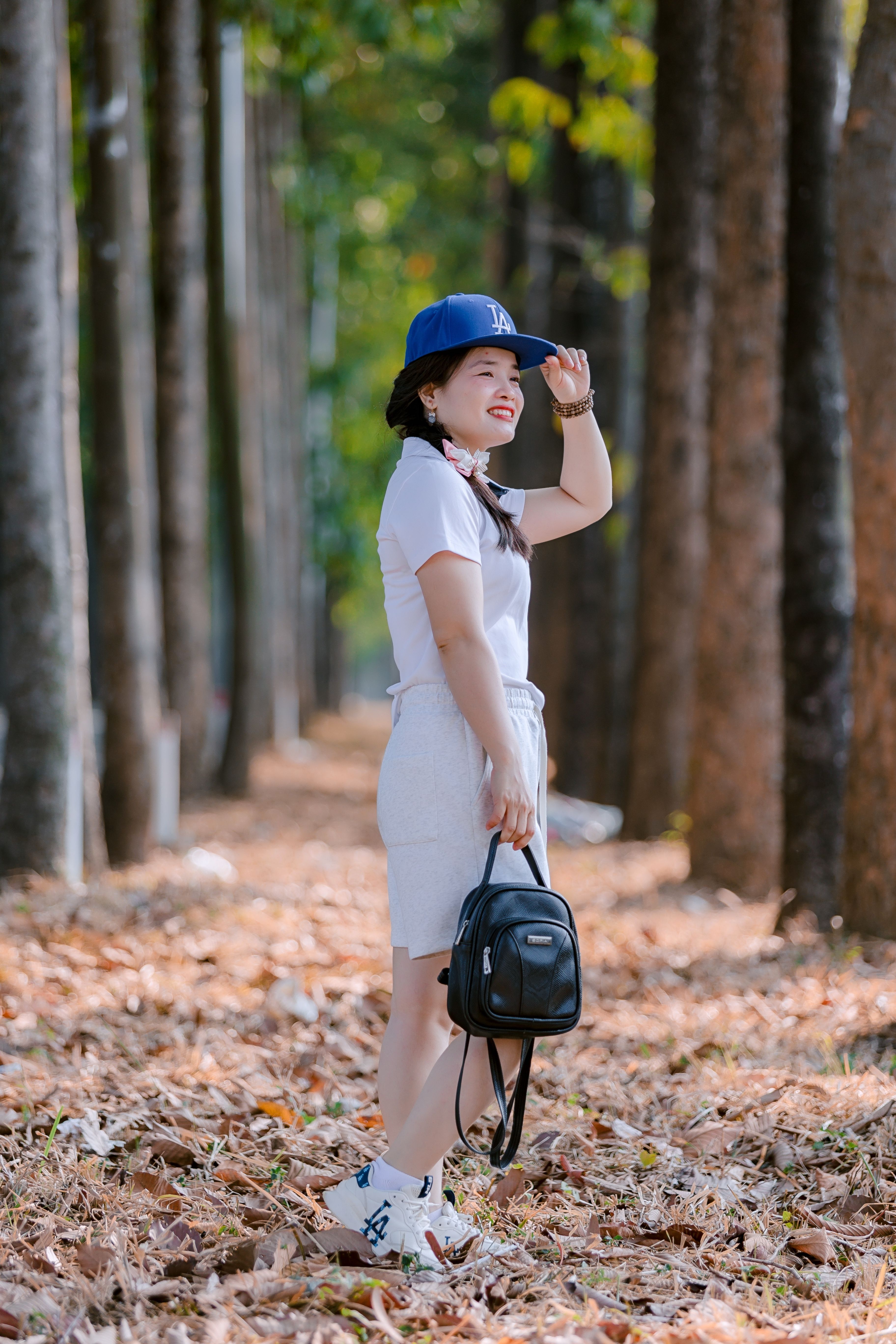 Stylish Woman Walking in Leafy Pathway · Free Stock Photo