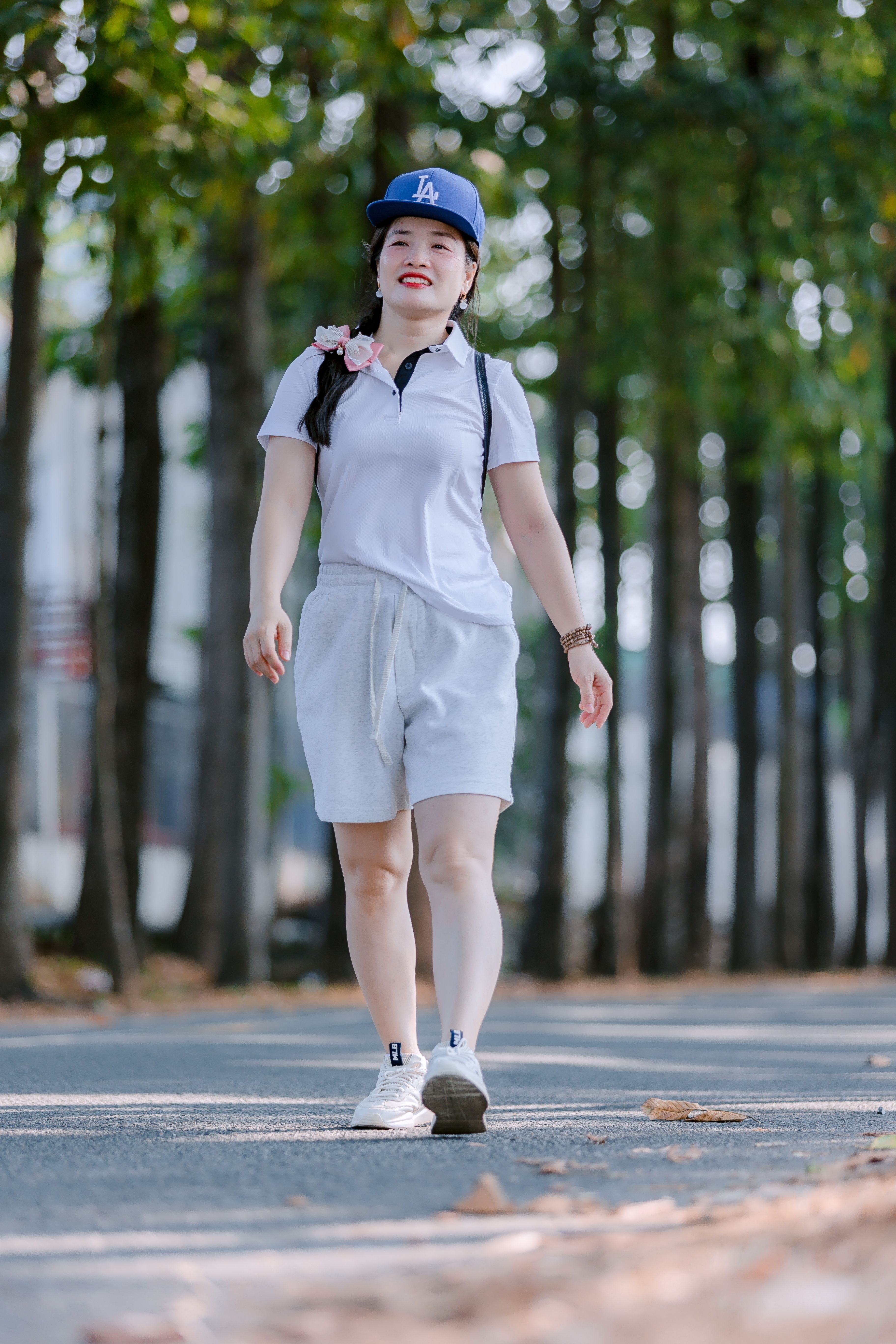 Woman in sports attire walking outdoors, surrounded by trees, exuding a relaxed vibe.