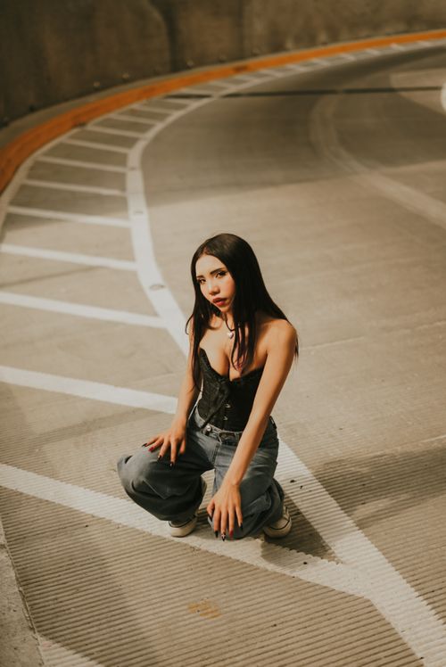 Free Young woman posing confidently on an empty urban street at night with dramatic lighting. Stock Photo