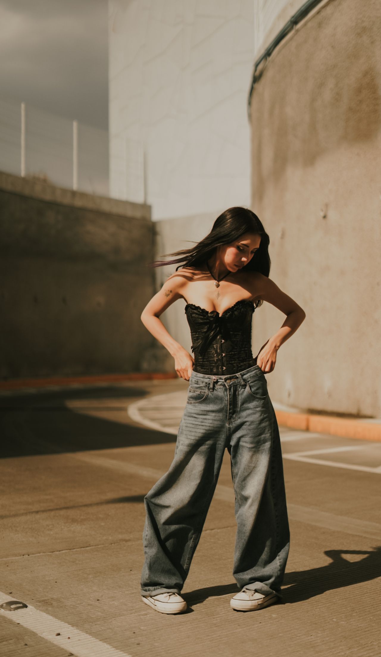 Woman in a black corset top and baggy wide-leg jeans with sneakers