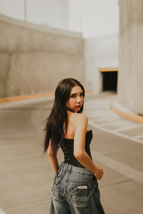 Free Young woman wearing trendy outfit in an urban parking area, showcasing casual street style. Stock Photo