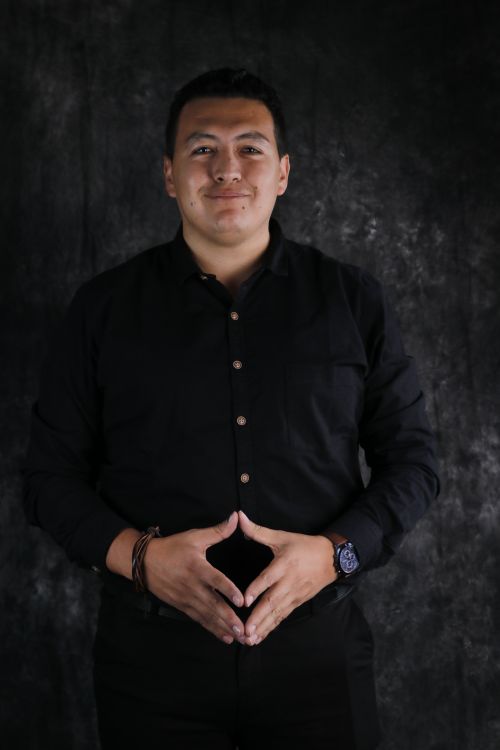 Free Smiling man in black shirt posing with hands clasped against dark background. Stock Photo
