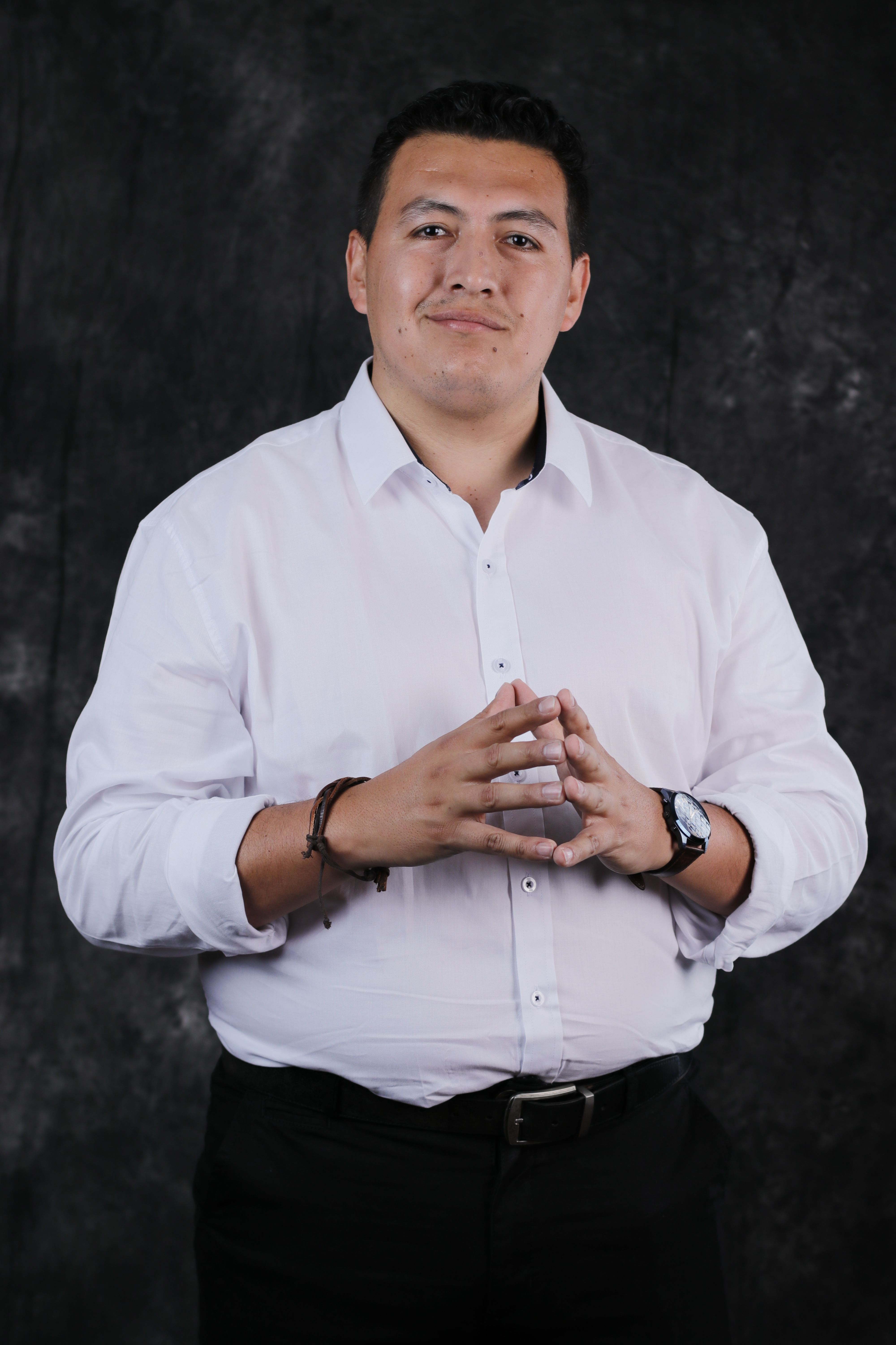 A confident businessman in a white shirt posing with folded hands, exuding professionalism and charisma.