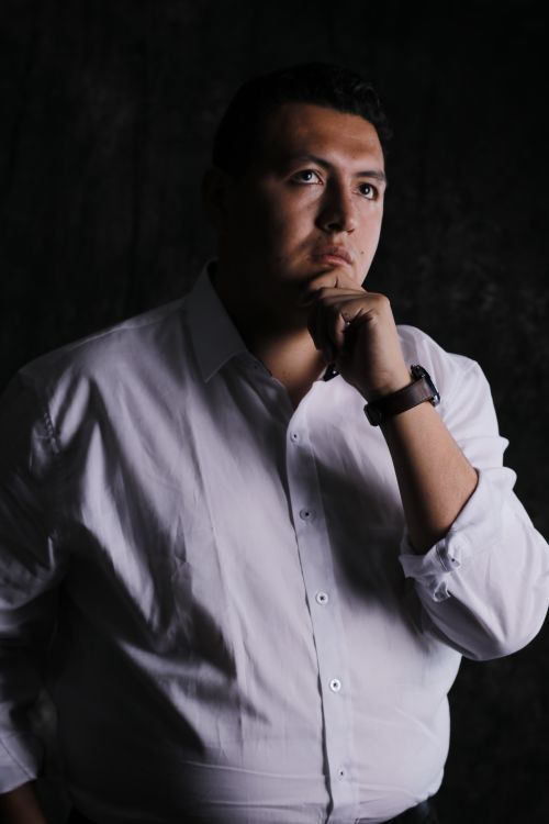 Free Portrait of a man in a white shirt, posing thoughtfully against a dark background. Stock Photo