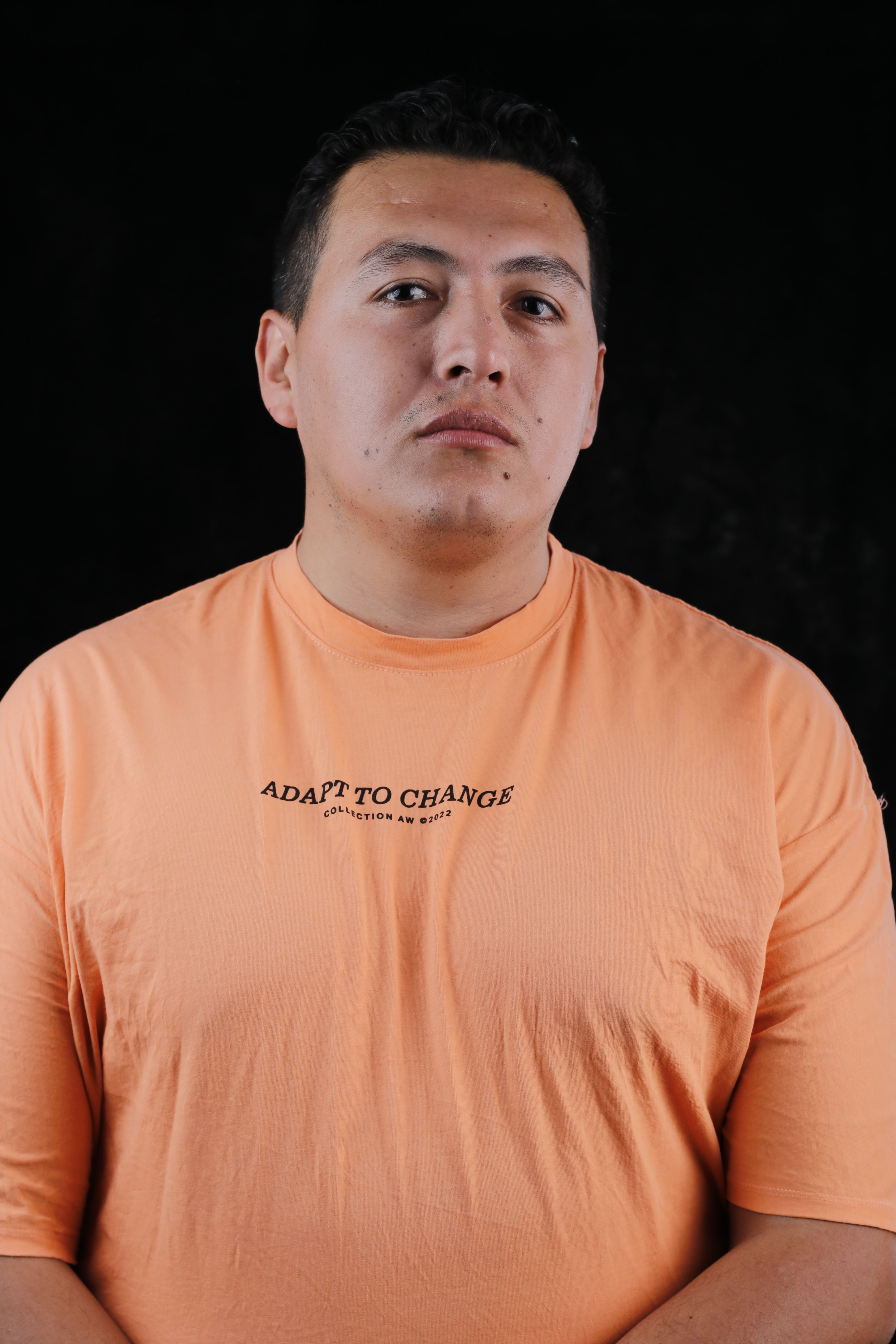 Man wearing orange shirt with 'Adapt to Change' text on black background.