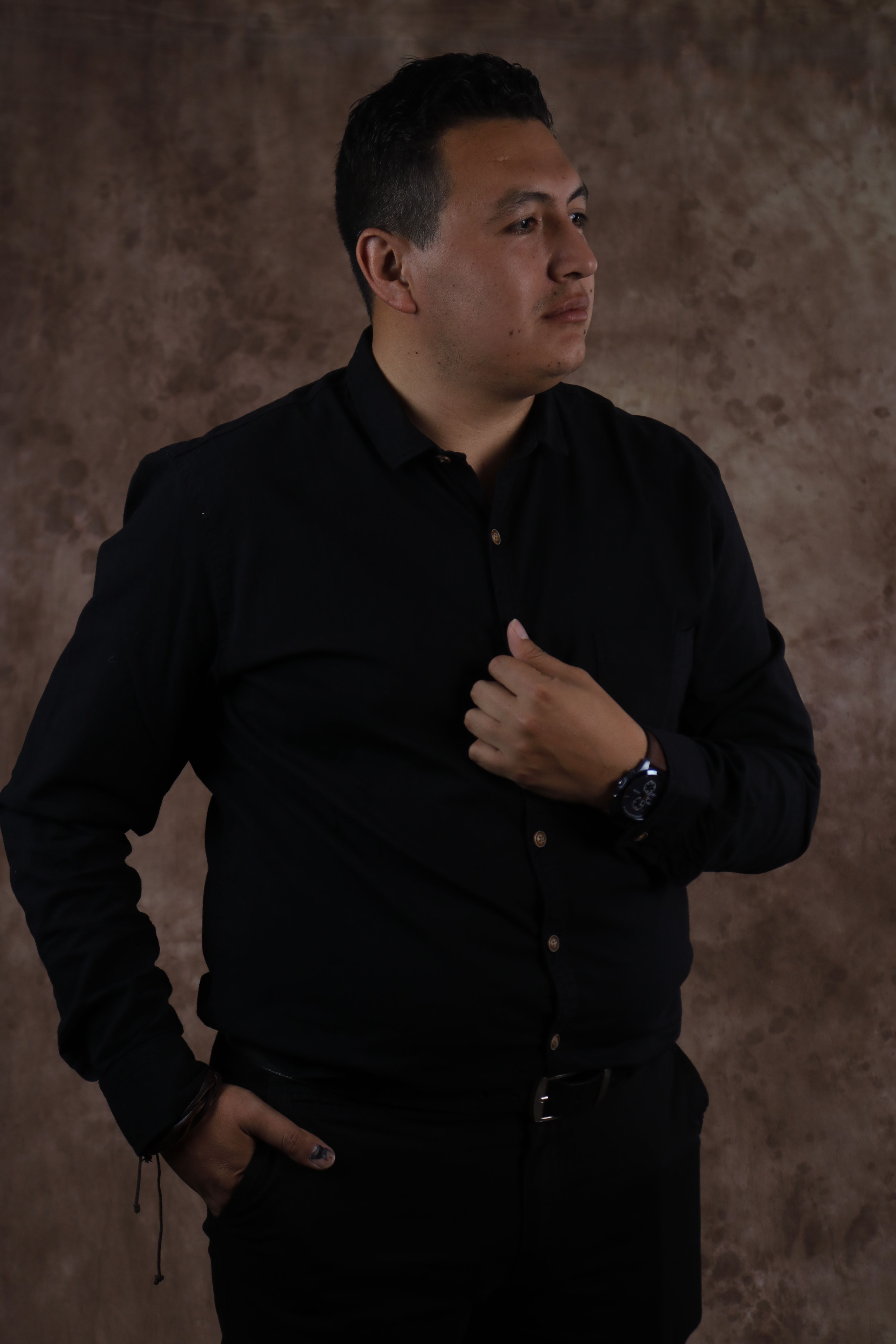 Sophisticated portrait of a man in a black shirt against a brown textured background.