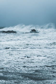 Captivating view of powerful ocean waves crashing at Wissant Beach, France, under a moody sky.