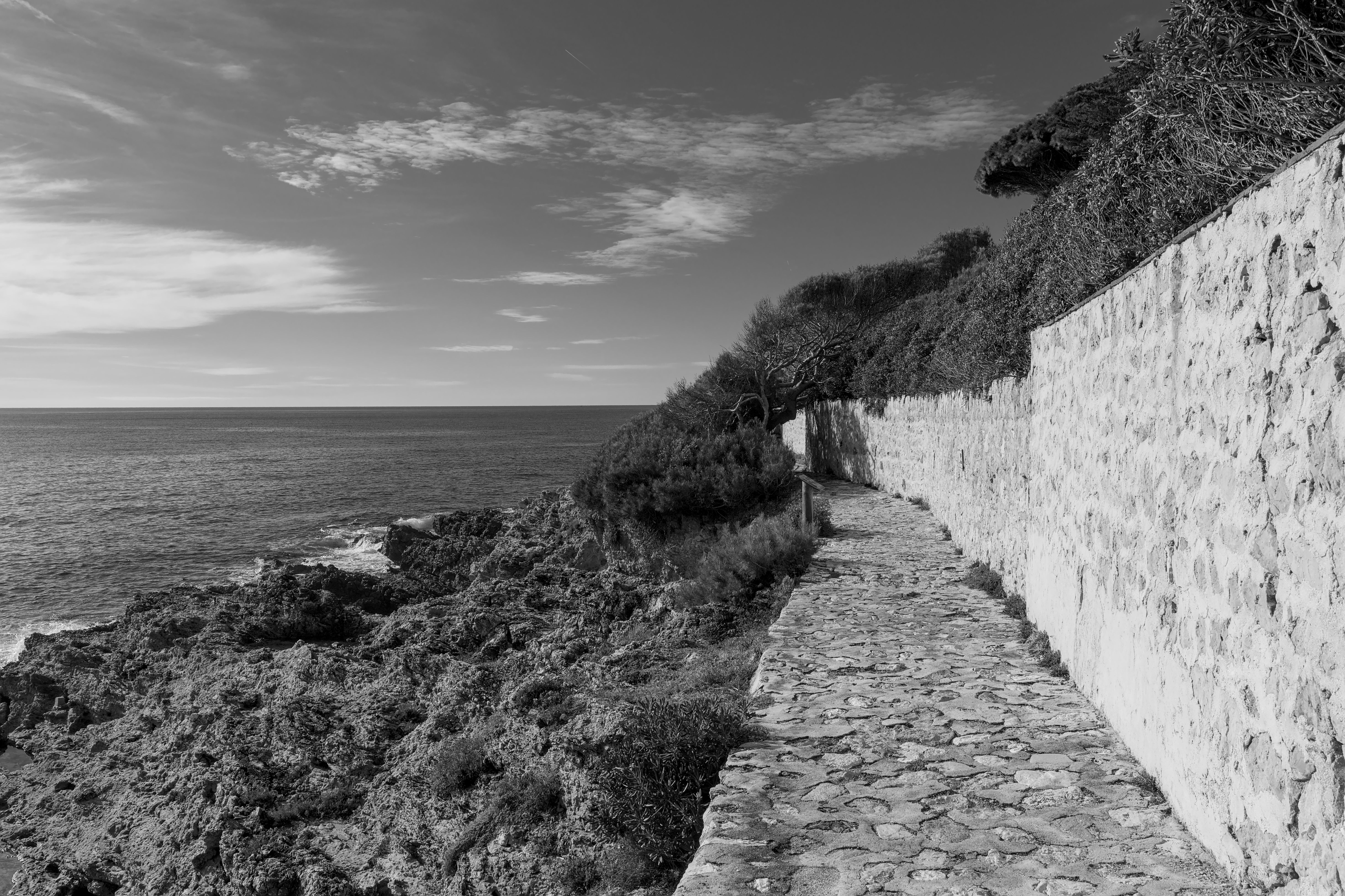 Black and white view of a rocky coastal path with ocean views in the French Riviera. Black and white view of a rocky coastal path with ocean views in the French Riviera.