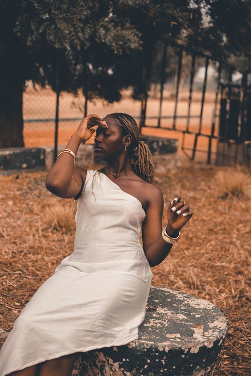 Free A woman in a white dress poses thoughtfully outdoors, capturing a serene and contemplative mood. Stock Photo