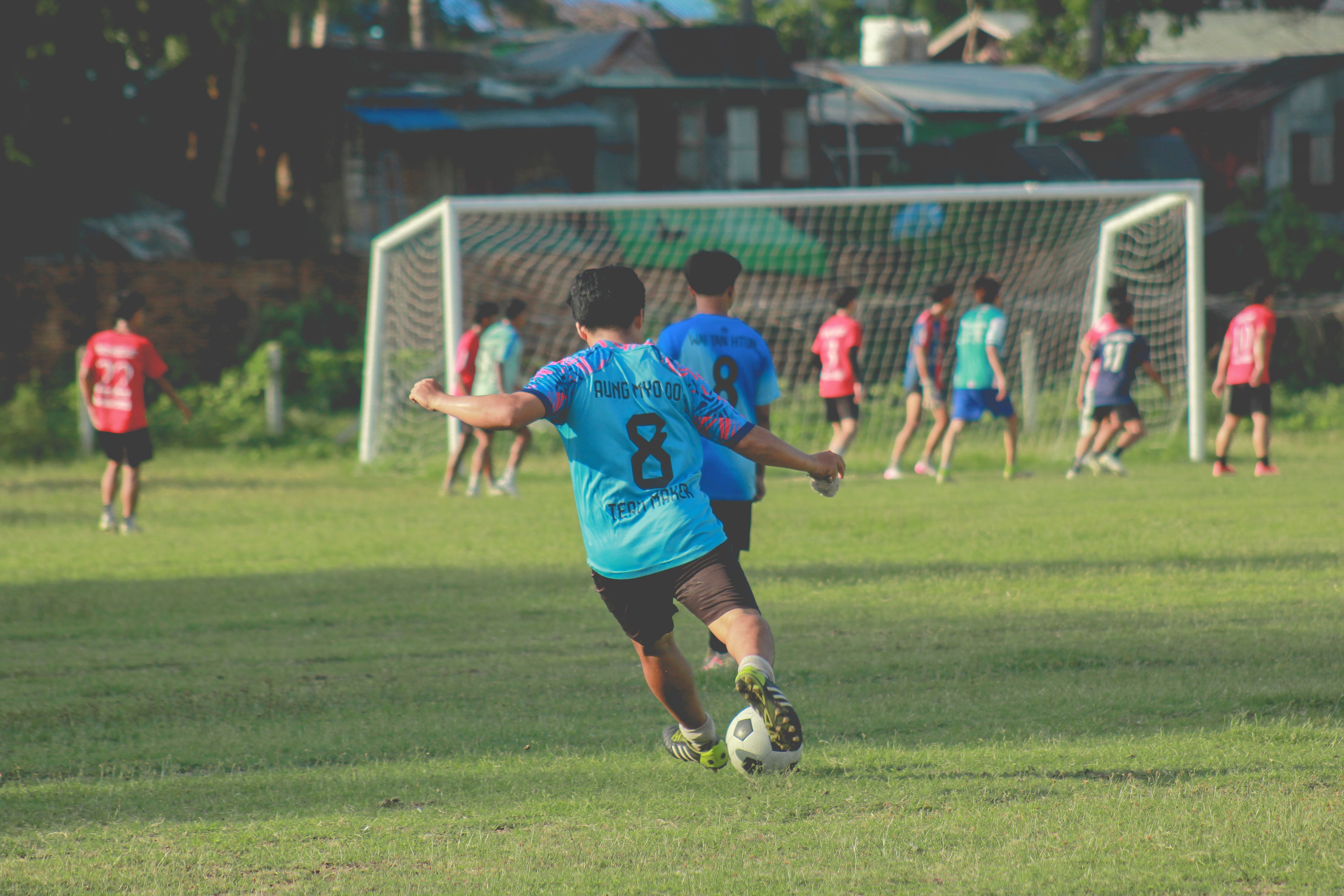 Boys playing football on a sunny day in Myawaddy, Myanmar, showcasing teamwork and agility.