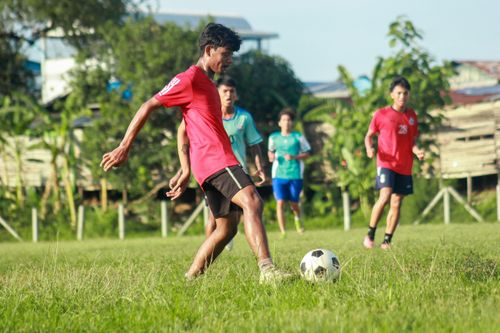 Free A group of young men enthusiastically playing soccer on a lush green field in Myawaddy, Myanmar. Stock Photo