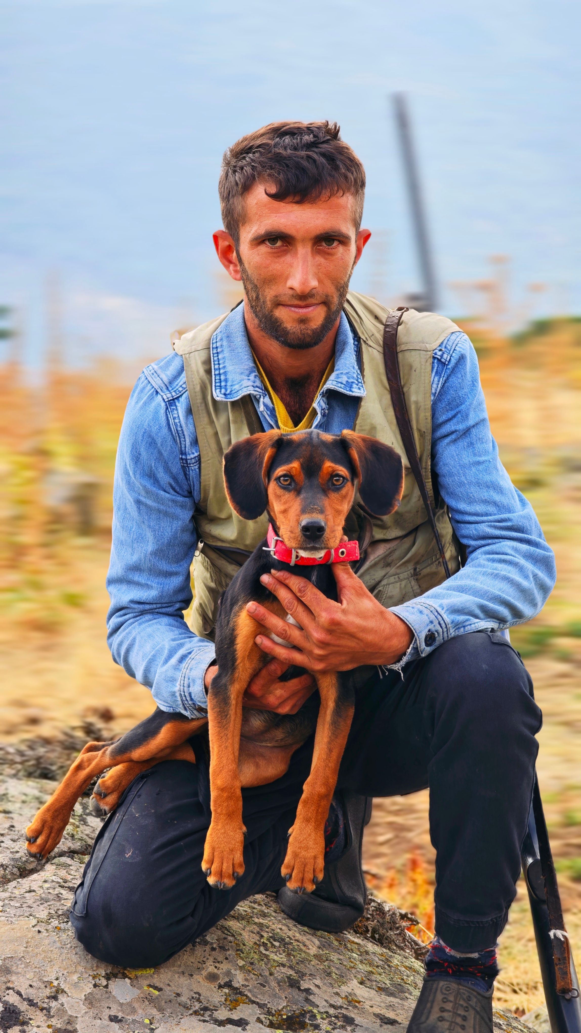 A young man holding a dog in an outdoor rural setting in Emet, Kütahya, Türkiye.