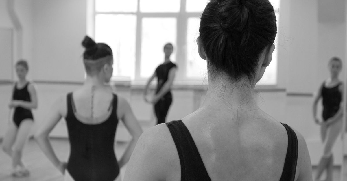 Black and white image of a ballet class with female dancers in a studio.