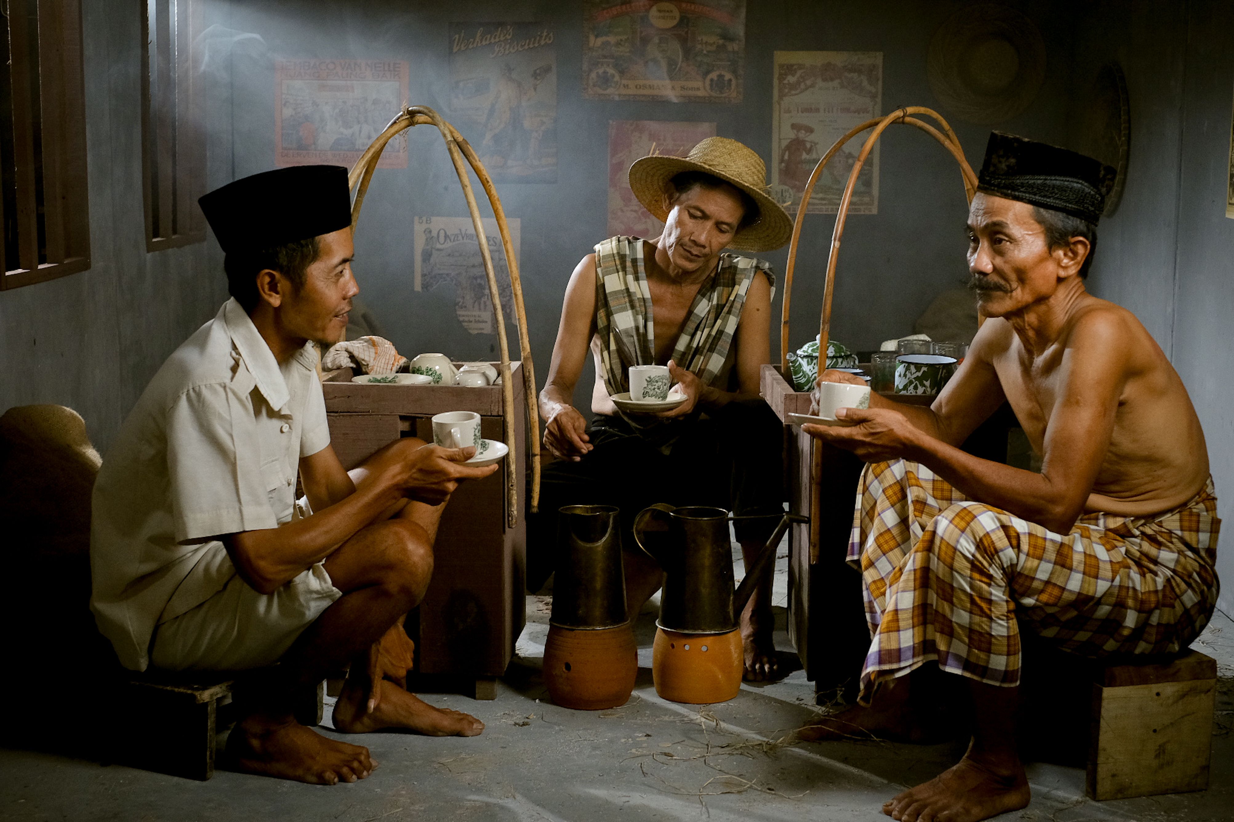 Fotomural Tres hombres indonesios disfrutan de un café tradicional en el interior de un local en Yakarta.