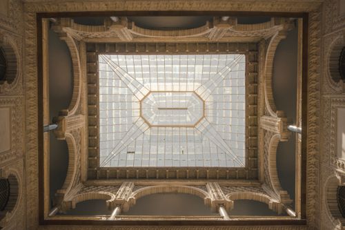 Free View of an ornate ceiling structure inside a landmark in Sevilla, Spain with detailed arches and glass roof. Stock Photo