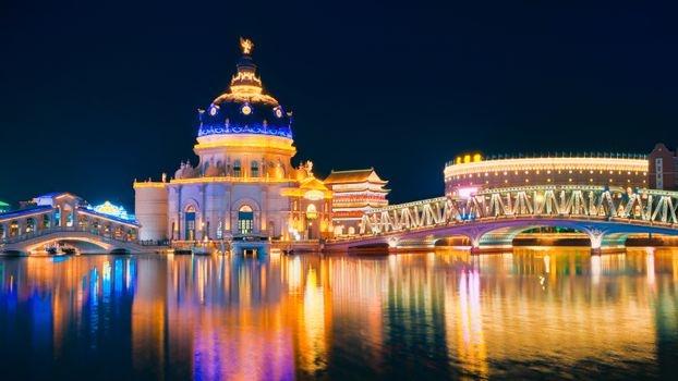Spectacular night view of illuminated architecture with vibrant reflections on water, showcasing modern lighting.