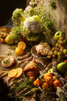 Elegant still life featuring fresh fruits, pastries, and floral arrangements in warm, vintage lighting.