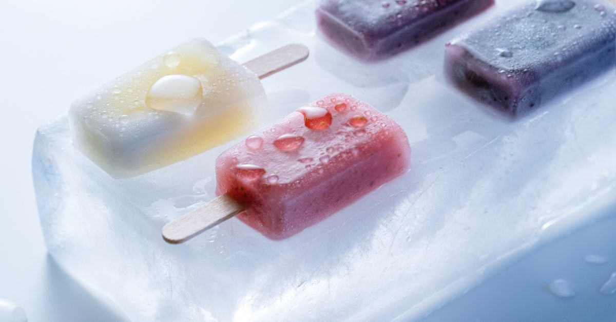 Deliciosos picolés de frutas mistas colocados sobre um bloco de gelo, perfeitos para se refrescar no verão.