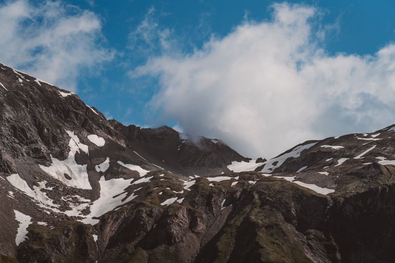 Breathtaking view of Austrian mountains with snow patches under a clear blue sky.
