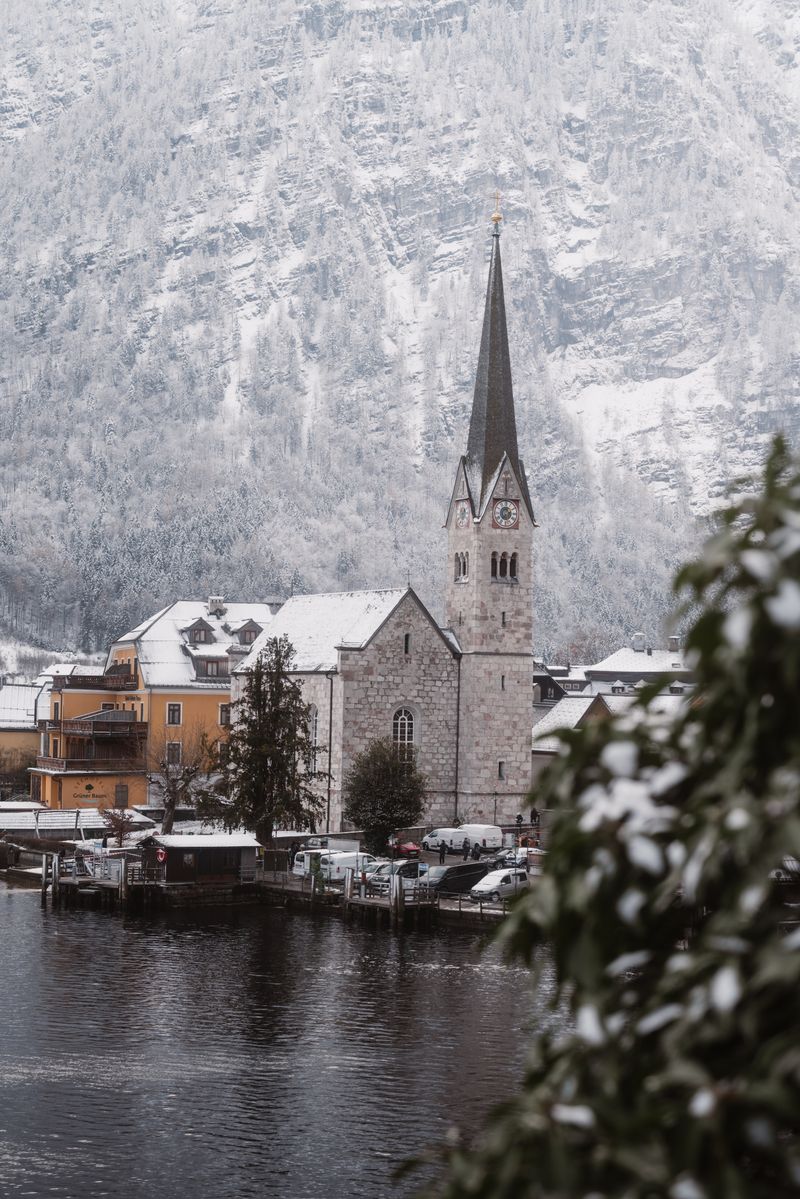 Serene winter scene featuring Hallstatt's iconic church against snowy mountains.